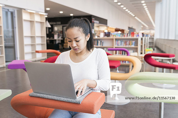 Junge Frau benutzt Laptop in der Bibliothek