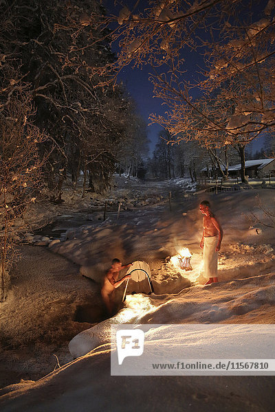 Two men bathing outdoors in winter at night