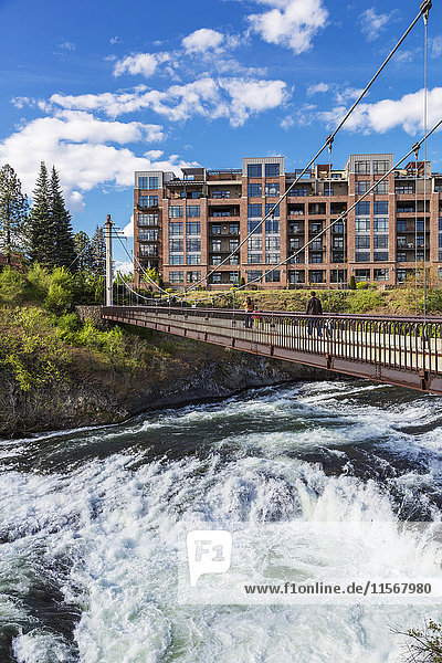 'People walk on a pedestrian bridge over Spokane River; Spokane  Washington  United States of America'
