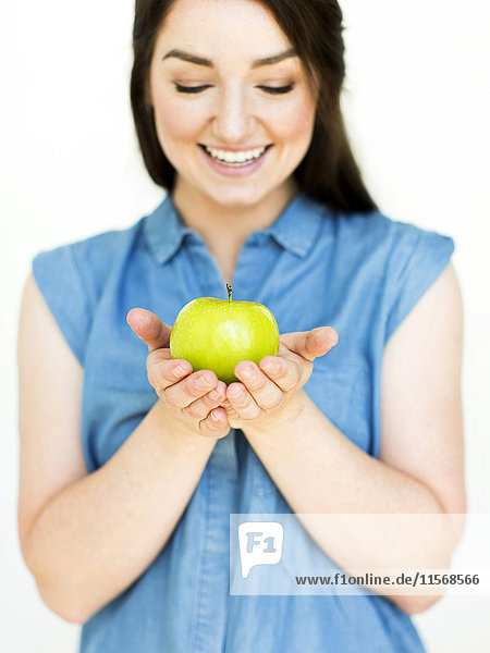 Woman wearing blue top holding green apple