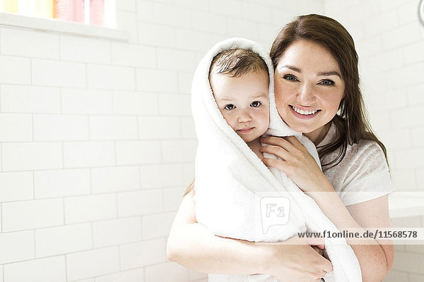 Mother wrapping son (4-5) in towel in bathroom