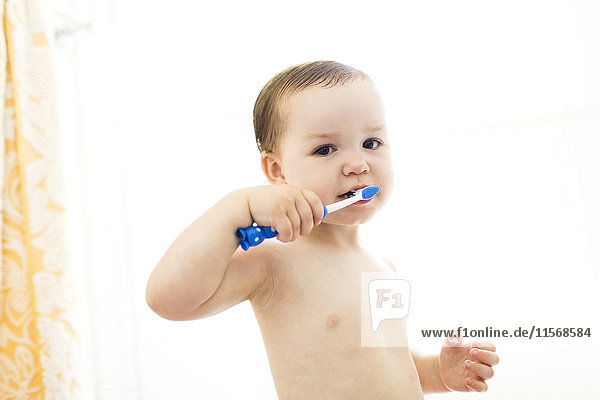 Shirtless boy (4-5) brushing teeth