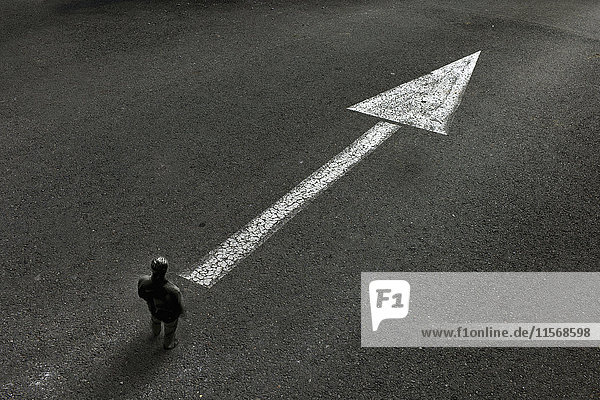Mann schaut auf gezeichneten Pfeil auf der Straße,  der die Richtung anzeigt