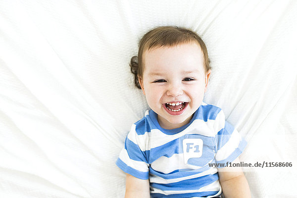 Boy (4-5) lying on bed and laughing