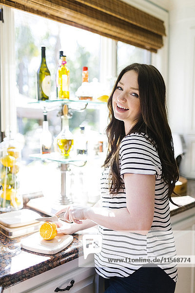 Frau schneidet Zitrone in der Küche