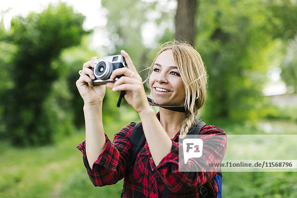 Junge Frau beim Fotografieren im Park