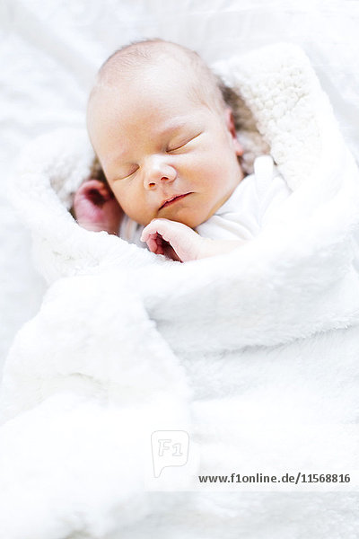 Kleiner Junge (2-5 Monate) schläft in weißer Decke