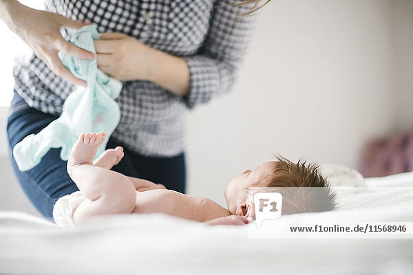 Junge Mutter wechselt die Windel eines kleinen Mädchens (0-1 Monate)