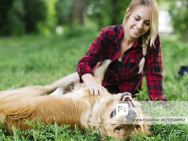 Young woman playing with golden retriever in park