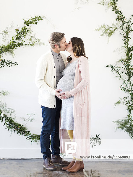 Porträt eines Mannes und einer schwangeren Frau  die sich küssen