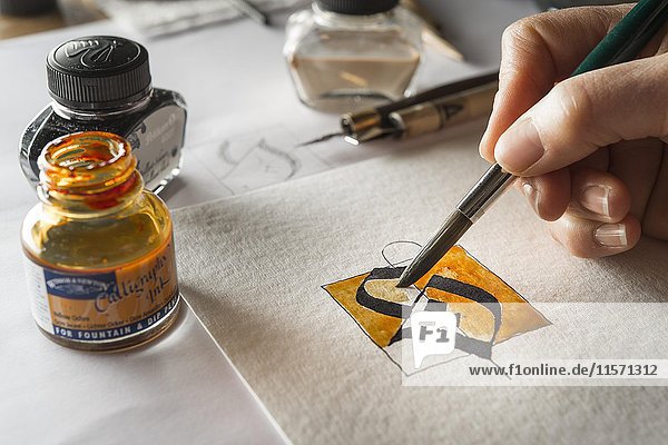 Kalligraphie-Atelier  Hand malt Oberfläche mit Pinsel  Buchstabe S auf Torchon-Papier  Tintenfässer und Füllfederhalter im Hintergrund  Seebruck  Oberbayern  Deutschland  Europa