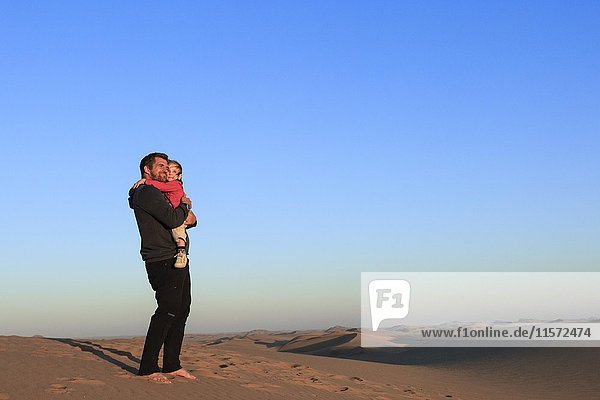 Father holding his baby daughter in her arms  Namib Desert  Langstrand  Swakopmund  Erongo Region  Namibia  Africa