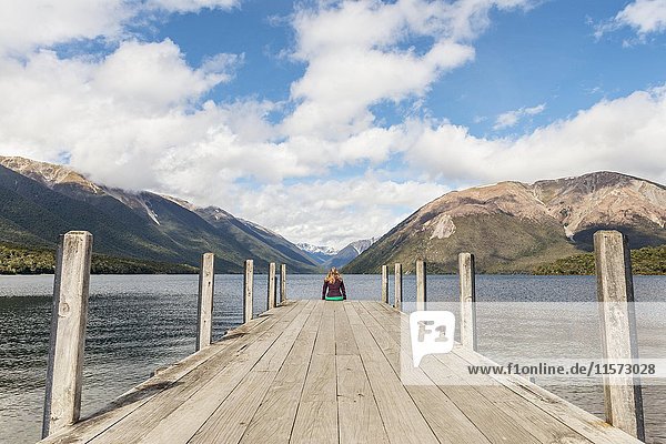Woman sitting on dock  view of Lake Rotoiti  Nelson Lakes National Park  Tasman District  Southland  New Zealand  Oceania