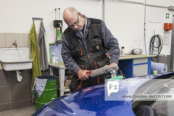 Coachbuilder master with the polishing machine on the car  Düsseldorf  North Rhine-Westphalia  Germany  Europe