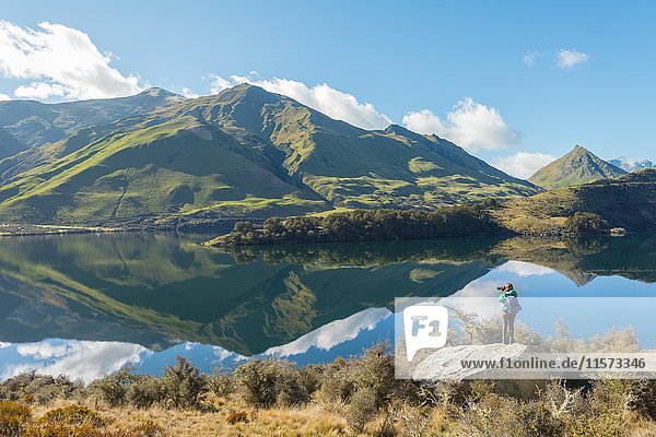 Hiker standing on rocks  mountains reflecting in lake  Moke Lake near Queenstown  Otago Region  Southland  New Zealand  Oceania