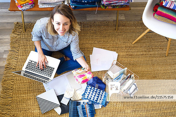 Portrait einer Innenarchitektin mit Laptop auf dem Boden im Einzelhandelsstudio
