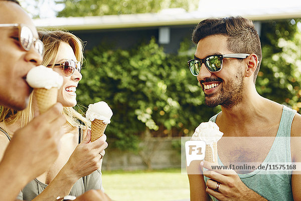 Male and female friends eating ice cream cones in park