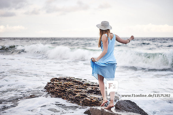 Frau genießt Spaziergang auf Felsen im Meer