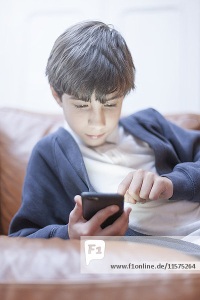 Junge spielt mit Smartphone auf dem Sofa