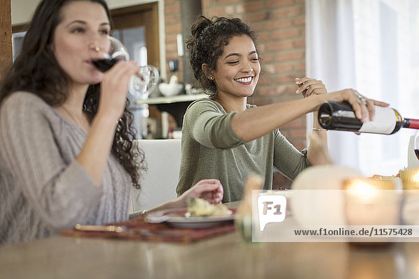 Zwei junge Freundinnen trinken Rotwein zum Essen am Küchentisch