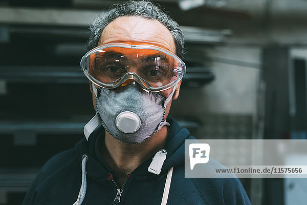 Porträt eines Metallarbeiters mit Staubmaske und Schutzbrille in der Schmiedewerkstatt
