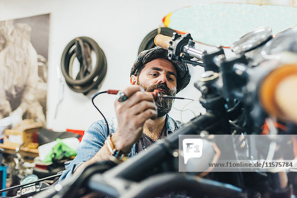 Mature man  working on motorcycle in garage