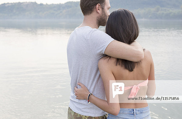 Couple hugging by river