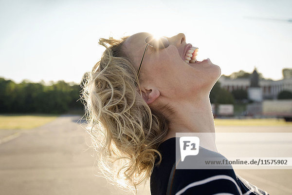 Mid adult woman laughing with head back in sunlight