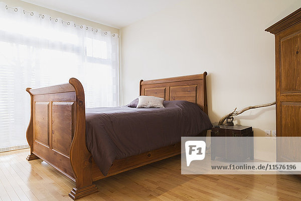 Antikes Holzschlittenbett im Hauptschlafzimmer der renovierten Erdgeschosswohnung im alten Landhausstil.