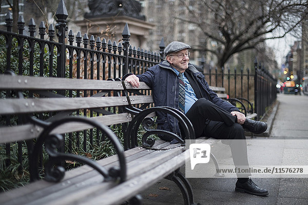 Mann sitzt lächelnd auf Parkbank  Manhattan  New York  USA