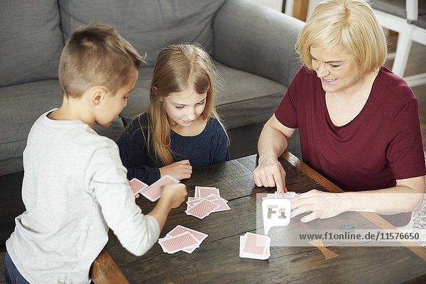 Großmutter und Enkelkinder beim Kartenspielen zu Hause