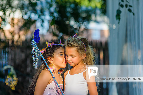 Two young girls dressed as fairies  girl whispering in friend's ear