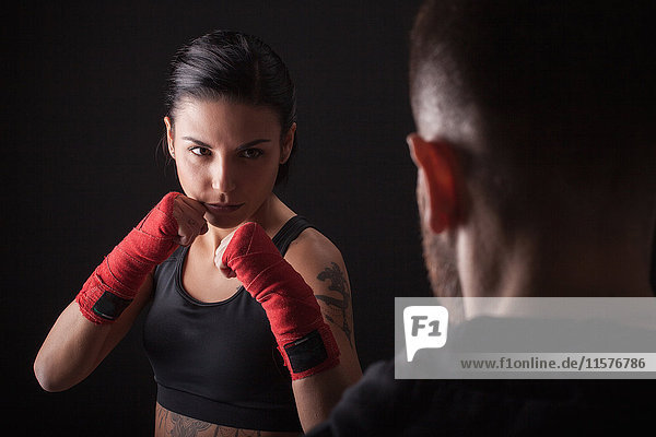Portrait of young woman in fighting stance  facing fitness trainer