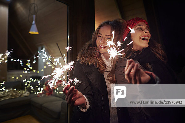 Friends playing with sparklers by chalet