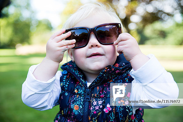 Porträt des Kleinkindes mit Sonnenbrille im Park