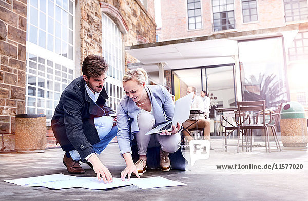 Businesswoman and man looking at paperwork on office patio floor