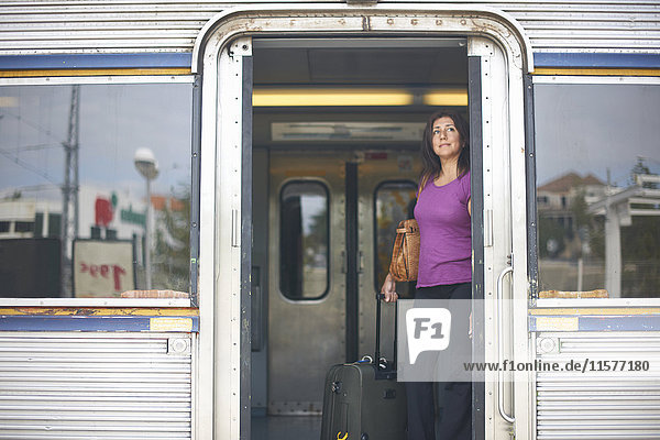 Mature woman looking out from train doorway on platform