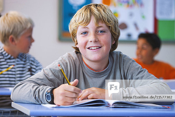 Porträt eines Jungen im Klassenzimmer  am Schreibtisch sitzend  bei der Klassenarbeit