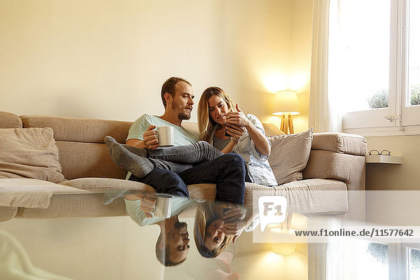 Mittleres erwachsenes Paar entspannt sich auf dem Sofa und schaut auf ein Smartphone