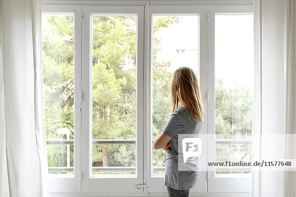 Woman at home  looking out of window  rear view
