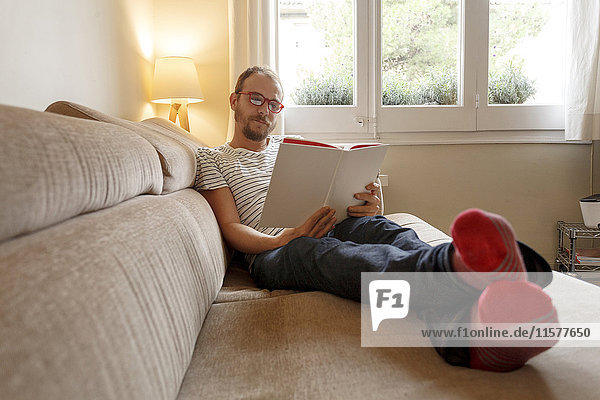 Man relaxing on sofa  reading book