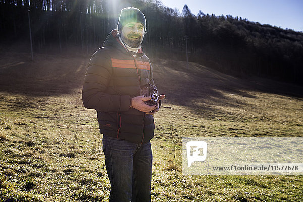 Porträt eines Mannes in ländlicher Umgebung  der eine Mittelformatkamera hält  Italien