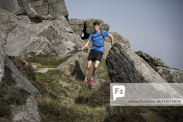 Male runner running and jumping down Stanage Edge  Peak District  Derbyshire  UK
