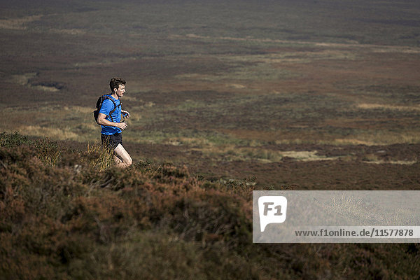 Male runner running down moorland