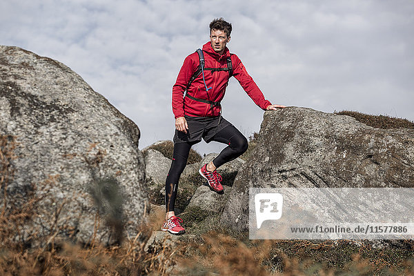 Male runner taking a break between boulders on Stanage Edge  Peak District  Derbyshire  UK