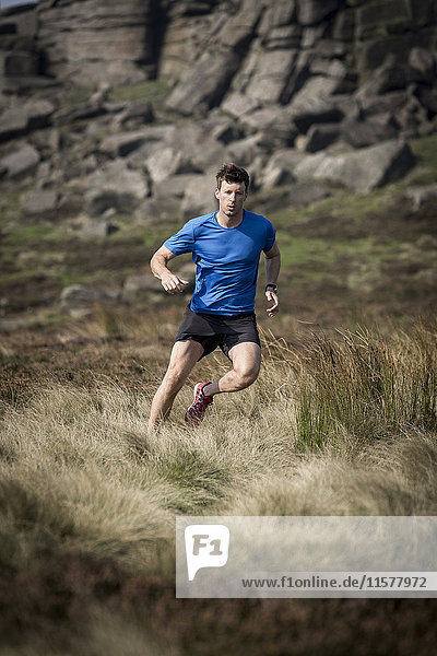 Male runner running down from Stanage Edge  Peak District  Derbyshire  UK
