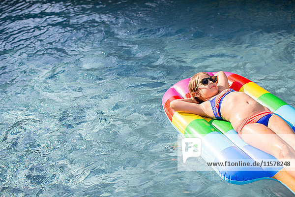 Mädchen im Bikini auf einem Schlauchboot liegend im Freibad