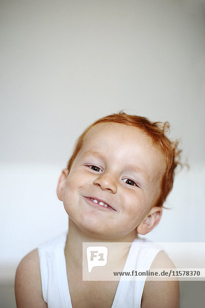 Porträt eines rothaarigen kleinen Jungen mit lächelndem Tank Top  drinnen