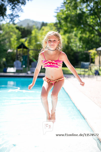 Portrait of girl jumping into outdoor swimming pool