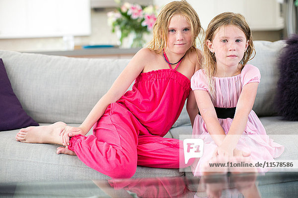 Porträt von zwei jungen Schwestern auf dem Sofa sitzend
